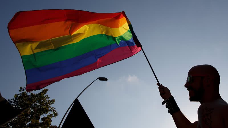 Pessoa segurando bandeira do orgulho LGBTQIAP+ - Getty Images