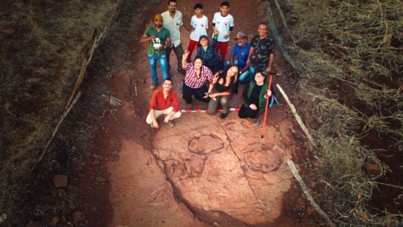 Equipe de pesquisadores ao lado das pegadas de dinossauros - Divulgação