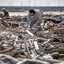 Homem fazendo buscas em destroços provenientes do tsunami de 2011 no Japão