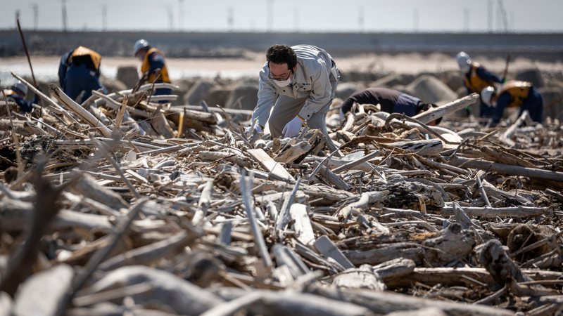 Homem fazendo buscas em destroços provenientes do tsunami de 2011 no Japão - Getty Images