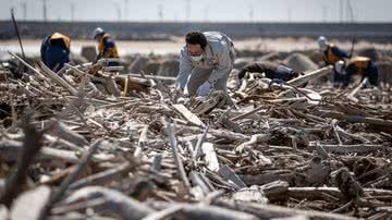 Homem fazendo buscas em destroços provenientes do tsunami de 2011 no Japão - Getty Images