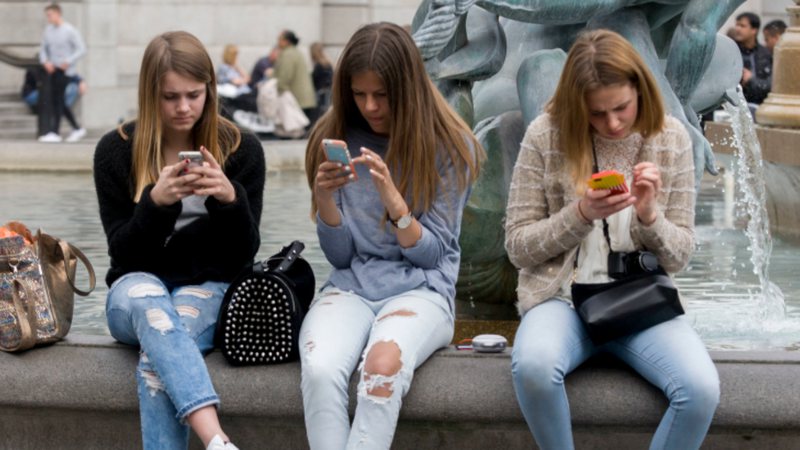 Três adolescentes usando o celular - Getty Images