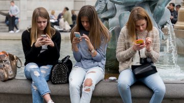 Três adolescentes usando o celular - Getty Images