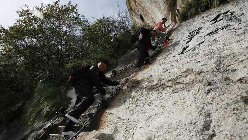 Homens subindo escada da 'Via Ferrata' - Getty Images