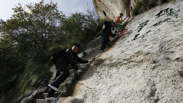 Homens subindo escada da 'Via Ferrata' - Getty Images