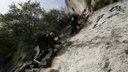 Homens subindo escada da 'Via Ferrata' - Getty Images