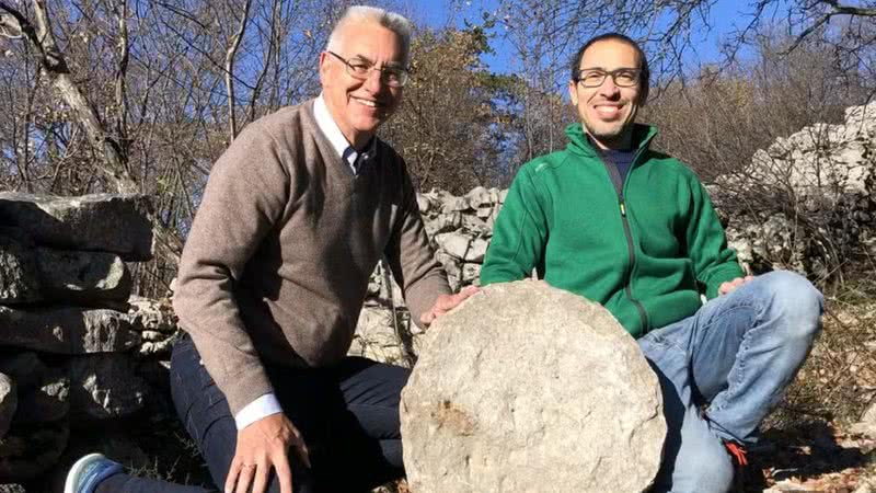 Paolo e Federico, dupla responsável pelo achado, posa com pedra perfurada com mapa de estrelas - Divulgação / Instituto Nacional Italiano de Astrofísica