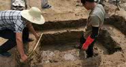 Arqueólogos medem uma das covas encontradas próximas ao rio - Divulgação