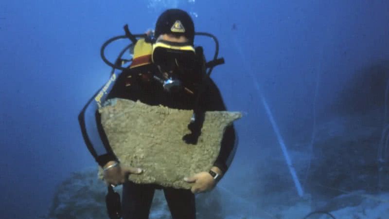 Arqueólogo mergulhador segurando grande placa de cobre encontrada em naufrágio - Divulgação/Texas A&M University/Cemal Pulak