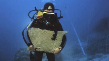 Arqueólogo mergulhador segurando grande placa de cobre encontrada em naufrágio - Divulgação/Texas A&M University/Cemal Pulak