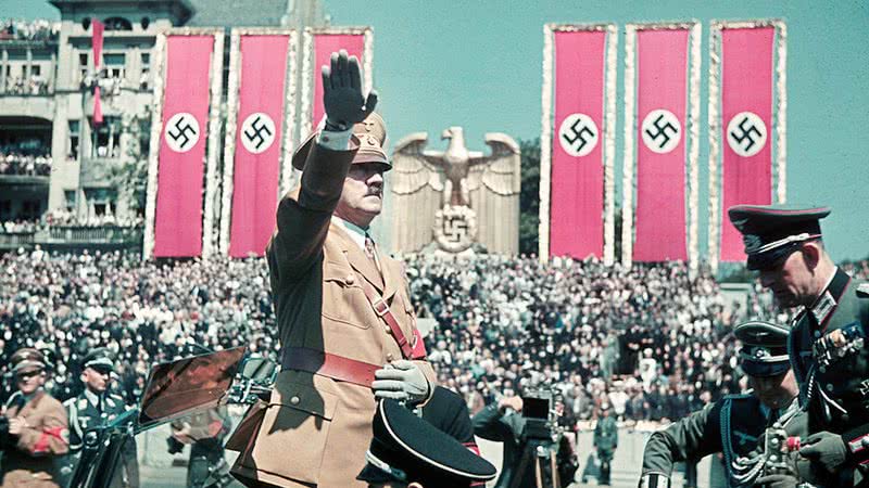 Hitler saudando seus membros, cercado por símbolos nazistas - Getty Images