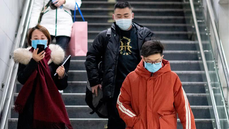 Chineses com máscaras faciais para a prevenção do vírus - Getty Images