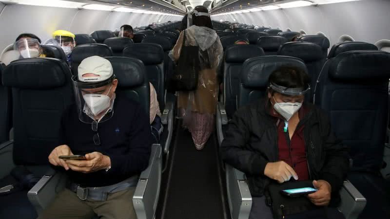 Pessoas aguardam decolagem de avião com máscaras - Getty Images