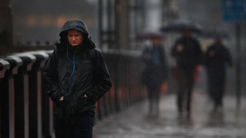 Homem andando na chuva com semblante triste - Crédito/Getty Images