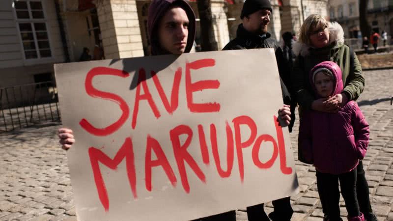 Pessoas seguram cartaz em defesa de Mariupol, na Ucrânia - Getty Images