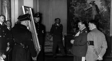 Hermann Goering mostra uma pintura confiscada ao líder alemão Adolf Hitler por volta de 1940 - Getty Images