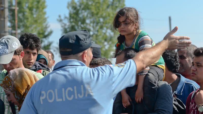 Policial ordenando grupo de imigrantes - Getty Images