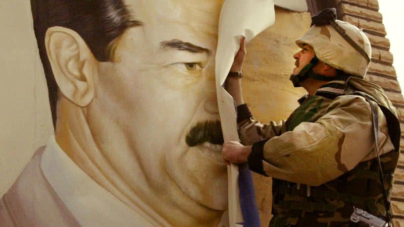 Militar estadunidense removendo cartaz com rosto de Saddam Hussein, durante a Guerra do Iraque - Getty Images