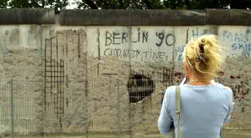 Imagem de uma mulher olhando para o Muro de Berlim, em 2001 - Getty Images