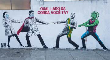 Grafite representando Jair Bolsonaro e o coronavírus em um cabo de guerra contra os trabalhadores da saúde - Getty Images