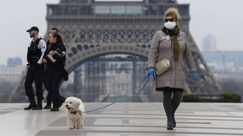 Imagem ilustra visitantes de máscara próximos a Torre Eiffel - Getty Images