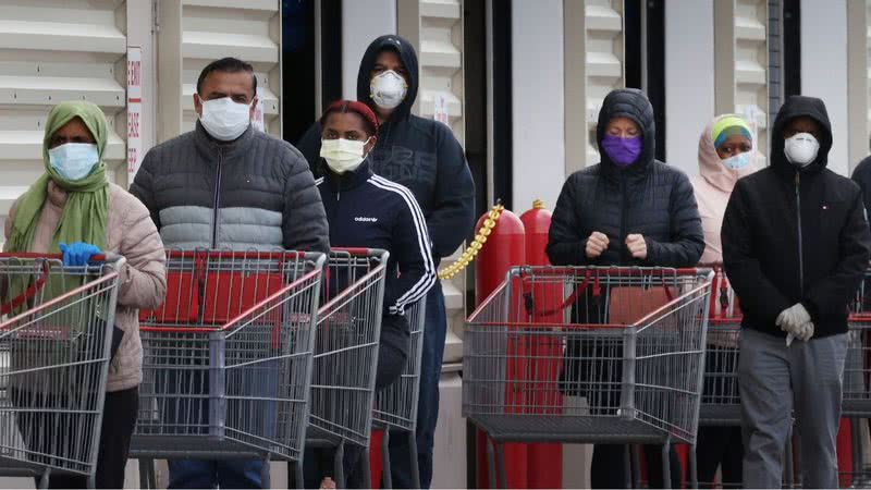 Fila com pessoas usando máscara facial - Getty Images