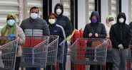 Fila com pessoas usando máscara facial - Getty Images