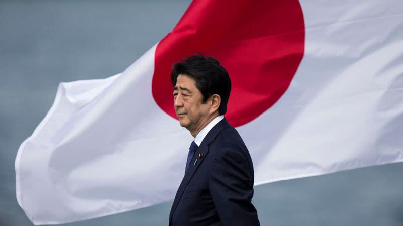 Shinzo Abe à frente da bandeira do Japão - Getty Images