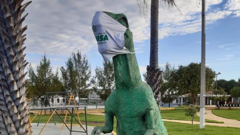 Foto de uma estátua de dinossauro com máscara - Divulgação/Twitter