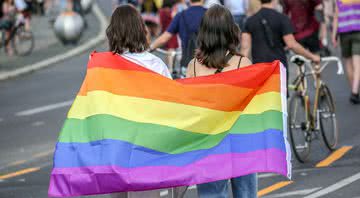 Mulheres com a bandeira LGBTQ+ em passeata - Getty Images