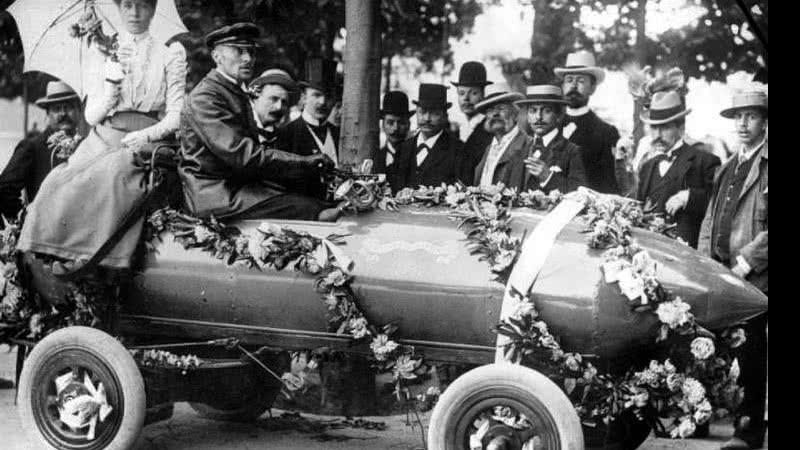 La Jamais Contente, recordista mundial de velocidade em 1899, fazendo então prodigiosos 106 km/h. O piloto Camille Jenatzy celebra a vitória com sua esposa.  - Domínio público