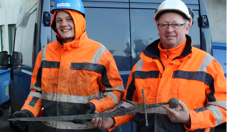 Os trabalhadores com a espada encontrada no esgoto - Divulgação/Museu Histórico de Aalborg