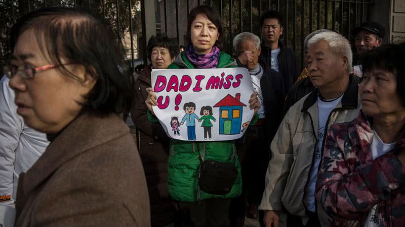 Protesto de familiares dos passageiros do voo MH370 um ano depois da tragédia, em 2015. Na foto, a esposa de um dos passageiros segura um cartaz que provavelmente foi feito por sua filha, escrito: "Pai, estou com saudades". - Kevin Frayer/Getty Images