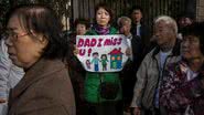 Protesto de familiares dos passageiros do voo MH370 um ano depois da tragédia, em 2015. Na foto, a esposa de um dos passageiros segura um cartaz que provavelmente foi feito por sua filha, escrito: "Pai, estou com saudades". - Kevin Frayer/Getty Images