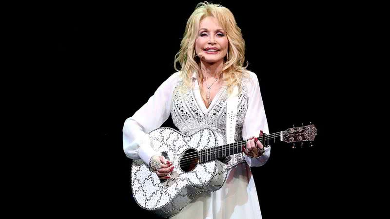 Dolly Parton com violão durante apresentação em 2014 - Getty Images