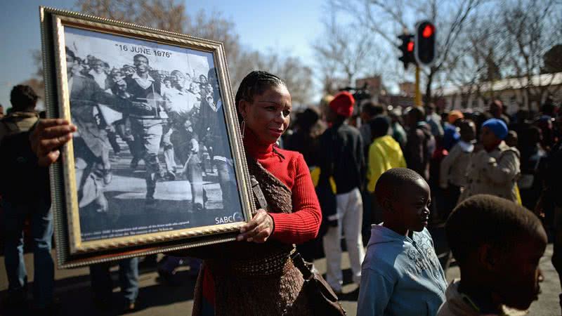 Mulher carrega foto do Levante de Soweto em marcha realizada em 2013 - Getty Images