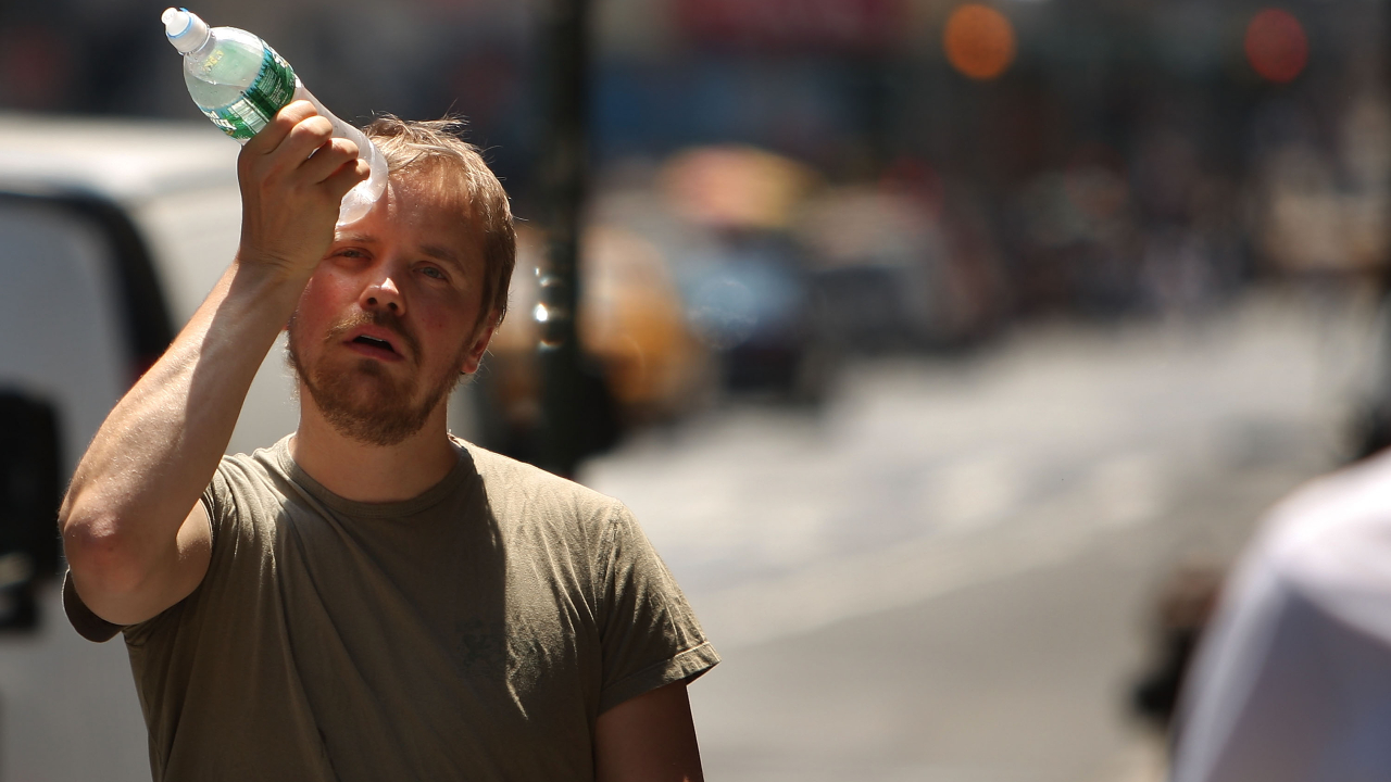 Homem tentando se refrescar com garrafa de água gelada