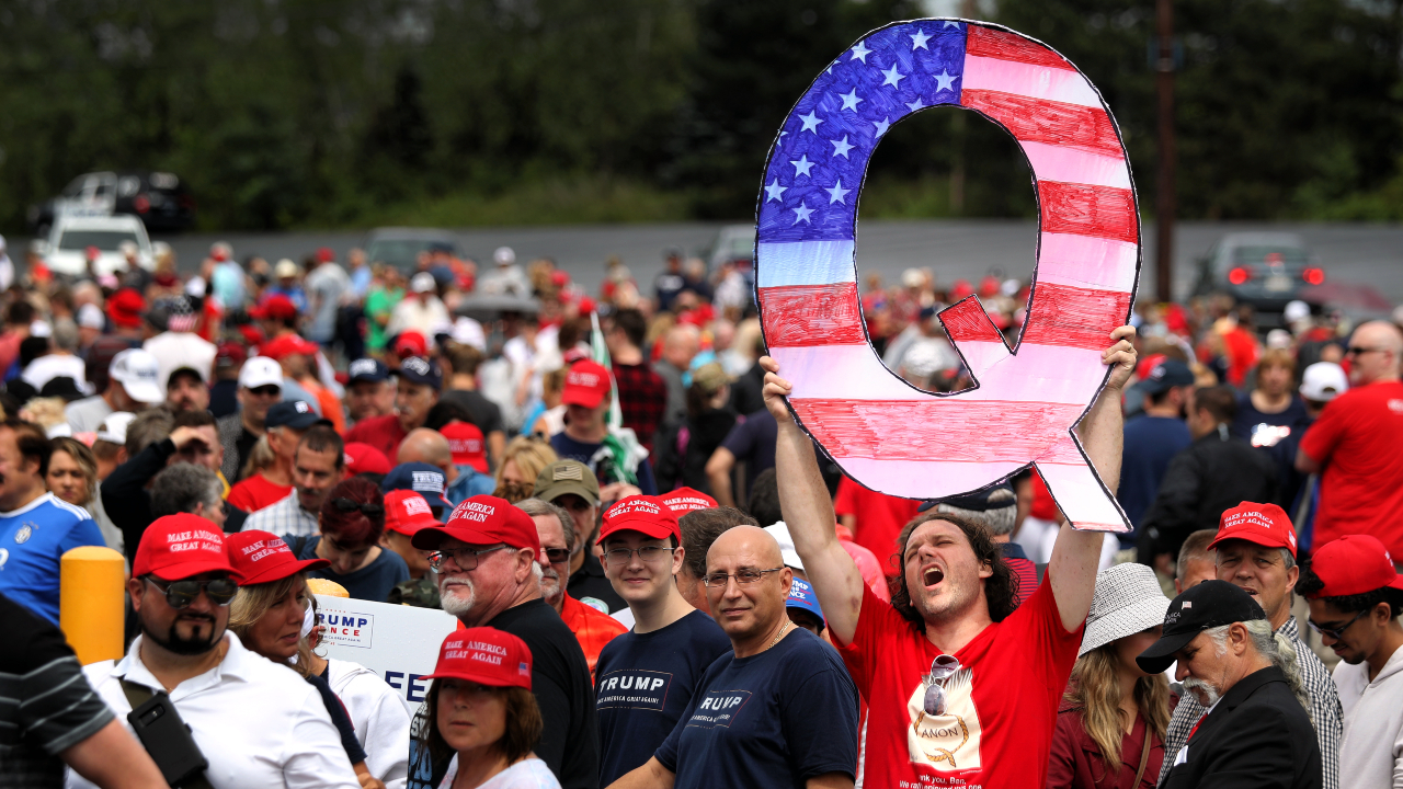 Membro do QAnon segurando um 'Q' gigante em evento pró-Trump