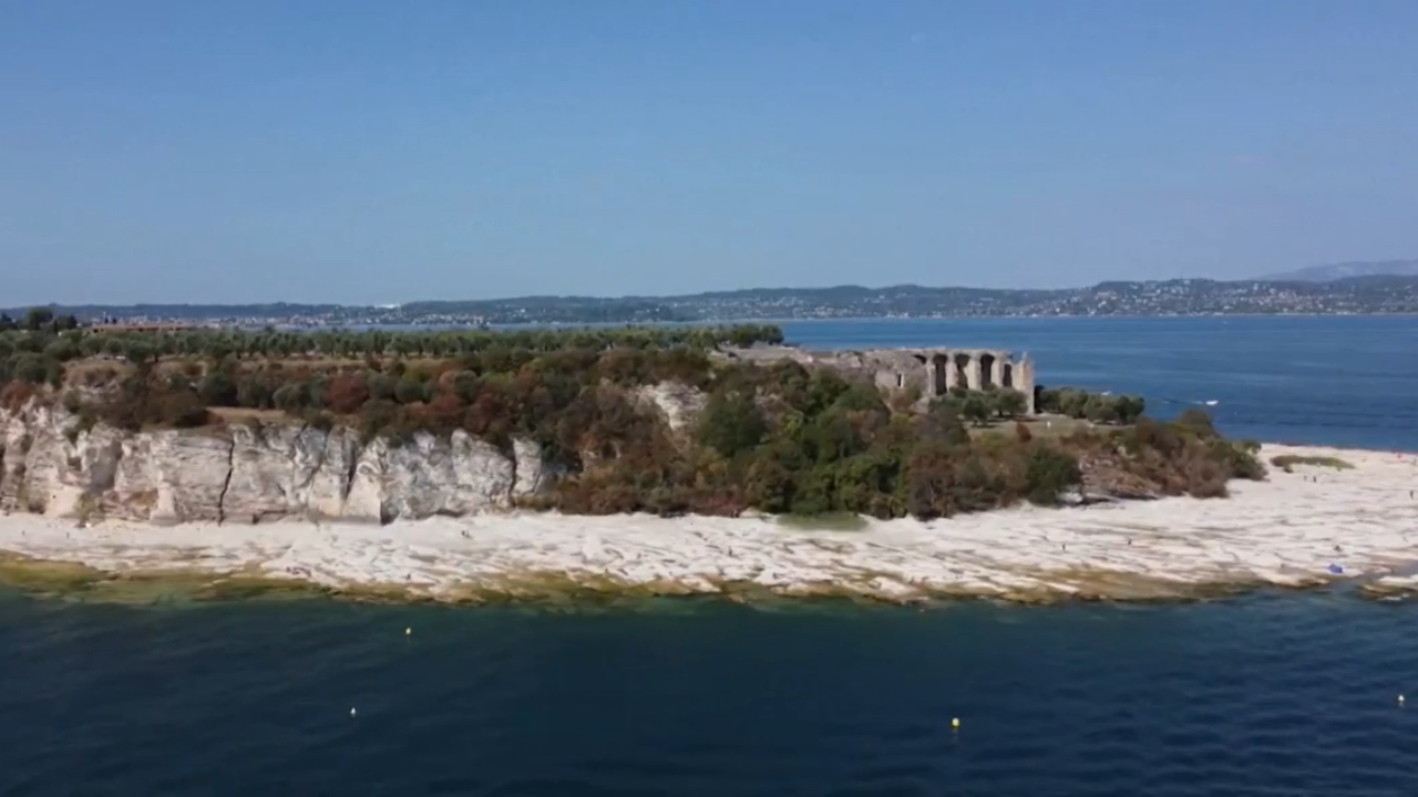 Vista aérea da 'orla' da praia rochosa formada em torno de ilha do Lago de Garda