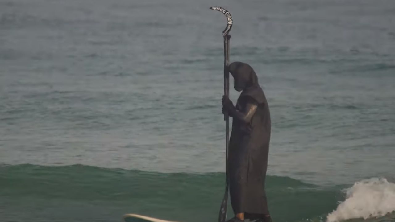 ‘Morte’ surfa na praia para alertar sobre os riscos de aglomeração
